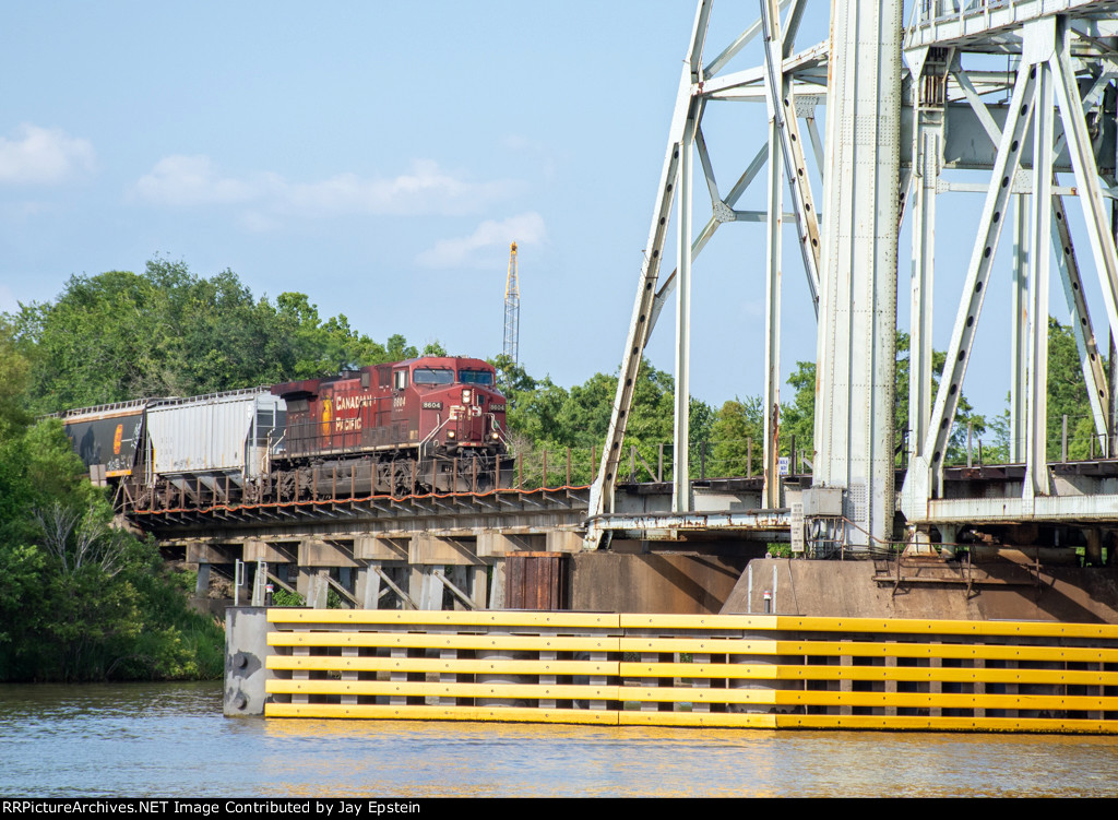 A westbound grain train starts across the Neches River Lift Bridge